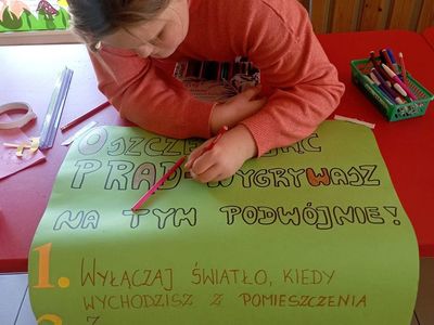 Dzieci z Placówki Wsparcia Dziennego z Lasek wykonują plakat o oszczędzaniu energii. 