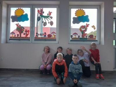 Dzieci z Niemicy pozują przy ozdobionych oknach w świetlicy.