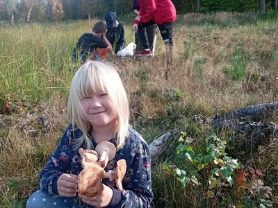 Dzieci z Placówki Wsparcia Dziennego w Laskach prezentują znalezione w lesie grzyby.
