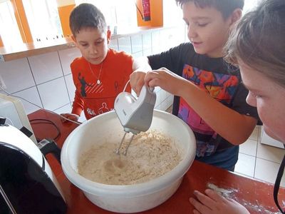 Wychowankowie z Placówki Wsparcia Dziennego w Laskach wyrabiają ciasto na chleb.
