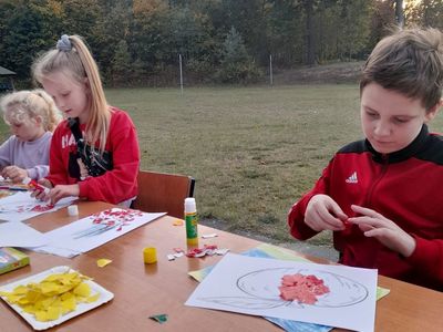 Dzieci z Sulechowa pozują do zdjęcia przy stole na dworze podczas zajęć plastycznych. 