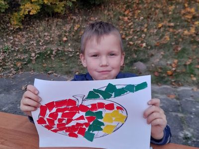 Chłopiec z Sulechowa pozuje do zdjęcia przy stole na dworze podczas zajęć plastycznych. 