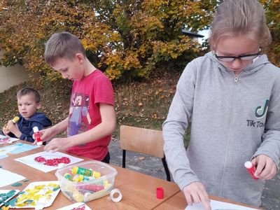 Dzieci z Sulechowa pozują do zdjęcia przy stole na dworze podczas zajęć plastycznych. 