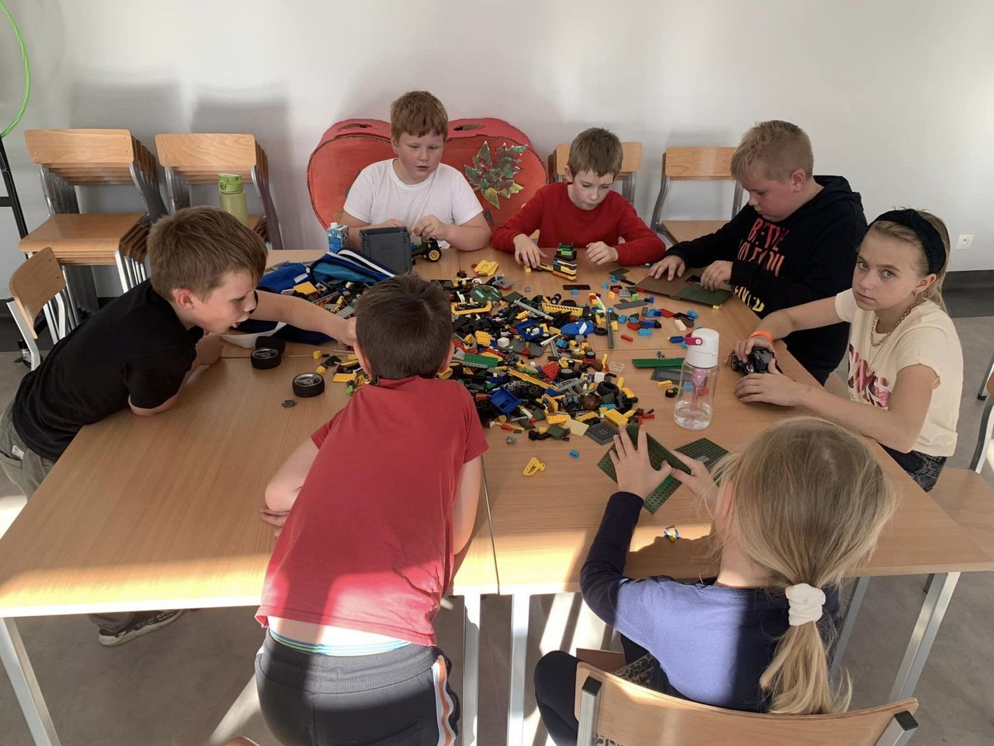 Dzieci ze Świetlicy Kultury w Malechowie układają pojazdy z klocków lego.