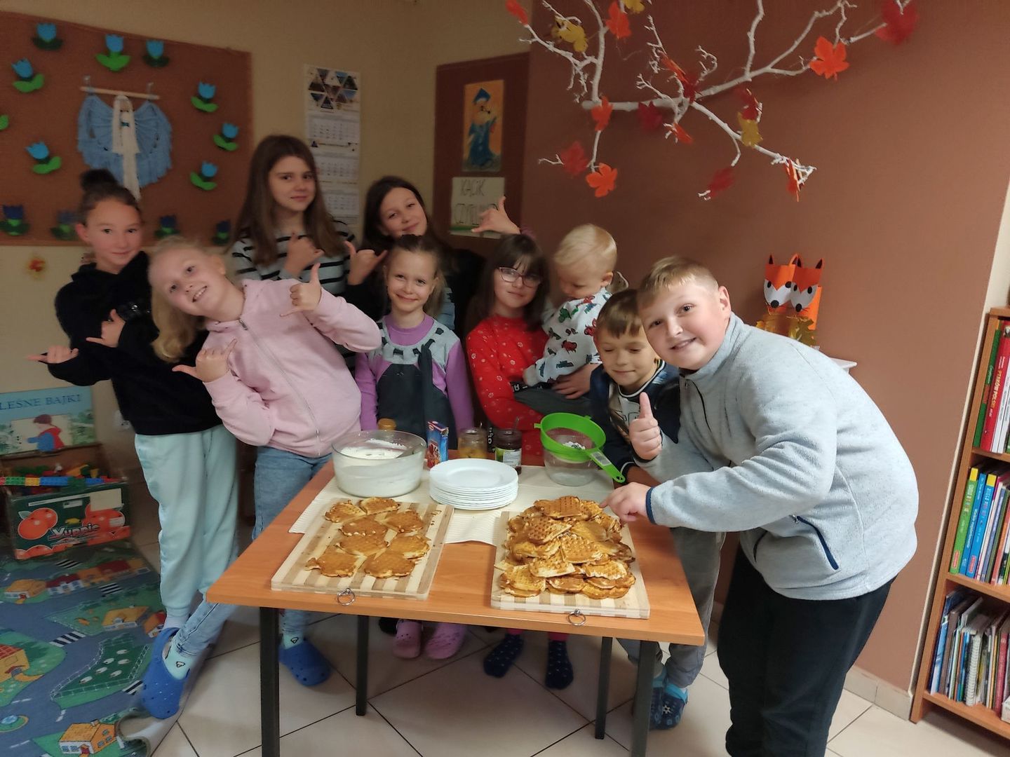 Dzieci z Placówki Wsparcia Dziennego w Kosierzewie pozują do zdjęcia przy stoliku pełnym gofrów.