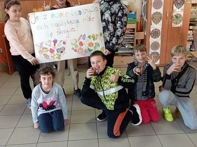 Dzieci z Lasek prezentują wykonany plakat i popijają sok. 