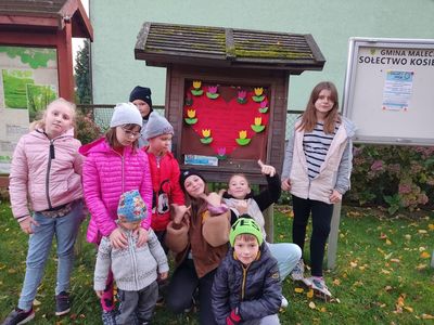 Dzieci z Kosierzewa pozują przy tablicy ogłoszeń z przygotowanym plakatem.