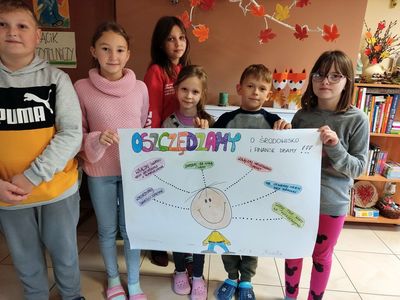 Dzieci z Placówki Wsparcia Dziennego w Kosierzewie prezentują wykonany plakat na temat oszczędzania.