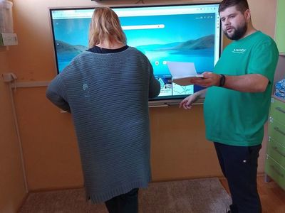 Dwie osoby podłączają tablicę multimedialną zakupioną w ramach programu "Aktywna tablica" do Szkoły Podstawowej w Ostrowcu.