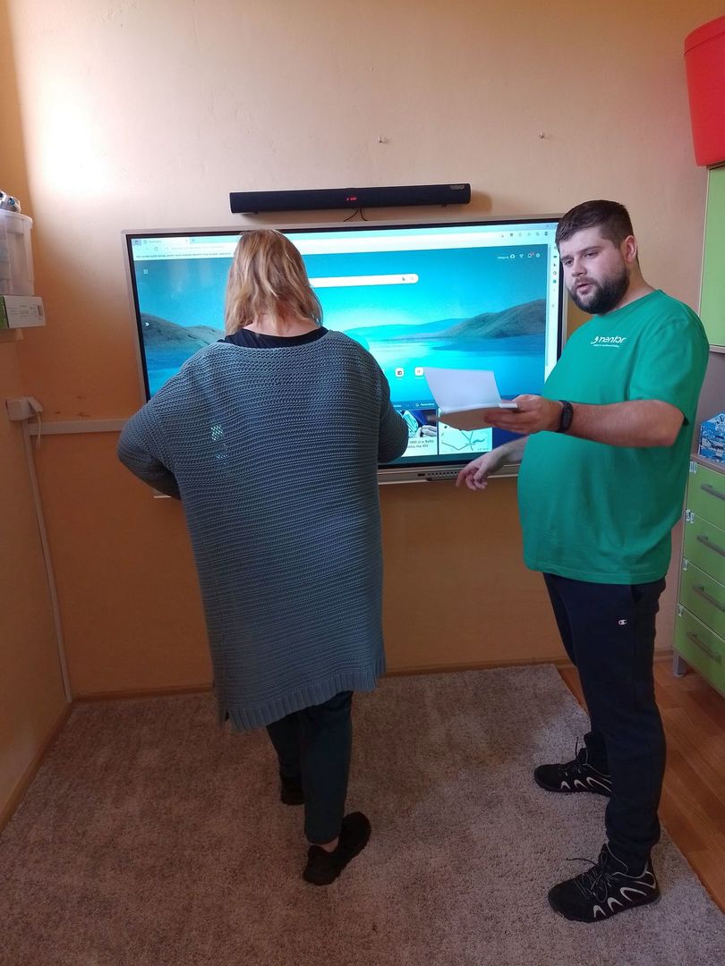 Dwie osoby podłączają tablicę multimedialną zakupioną w ramach programu "Aktywna tablica" do Szkoły Podstawowej w Ostrowcu. 