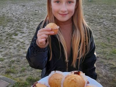 Dziewczynka z Placówki Wsparcia Dziennego w Sulechowie pozuje z przygotowanymi babeczkami.