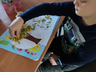Chłopiec z Placówki Wsparcia Dziennego w Kosierzewie wykleja jesienne drzewko. 