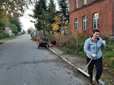 Dzieci wraz z opiekunami z Przystaw sprzątają liście. 
