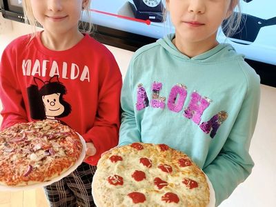Dwóch chłopów pozuje do zdjęcia z pizzą. 