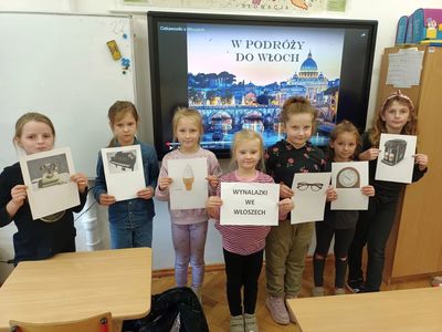 Dzieci z Lejkowa pozują do zdjęcia z kartami przedstawiającymi wynalazki z Włoch. 