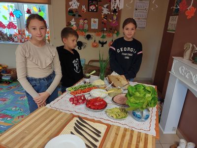  Grupa dzieci przy stole z produktami spożywczymi w Placówki Wsparcia Dziennego w Kosierzewie.