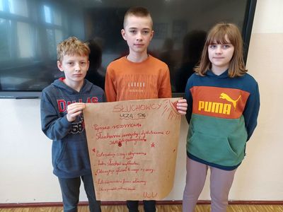 Uczniowie prezentują plakat ,,Jak się uczą słuchowcy?".