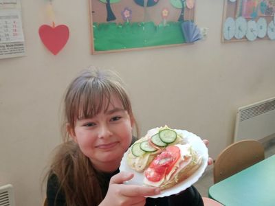 Dziewczynka z Placówki Wsparcia Dziennego w Niemicy pozuje do zdjęcia ze zdrową kanapką. 