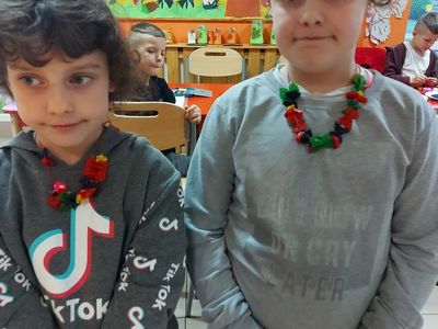 Dwoje dzieci z PWD Laski pozują do zdjęcia z kolorowym naszyjnikiem. 