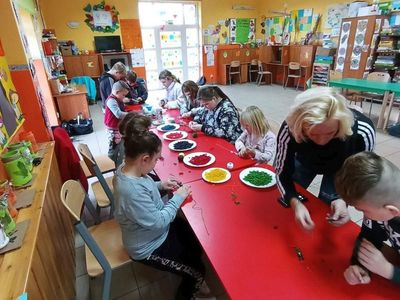 Dzieci z PWD Laski z wychowawczynią przygotowują kolorowe naszyjniki z makaronu. 