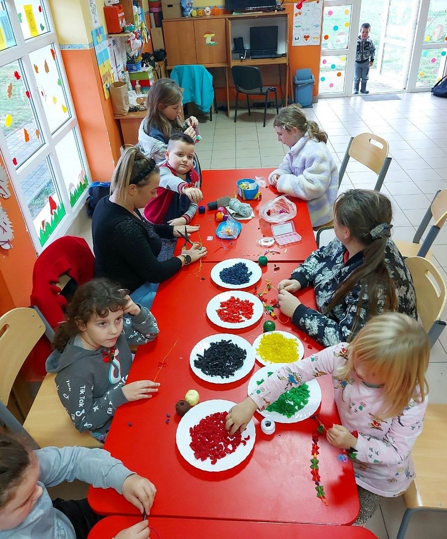 Dzieci z PWD Laski z wychowawczynią przygotowują kolorowe naszyjniki z makaronu. 
