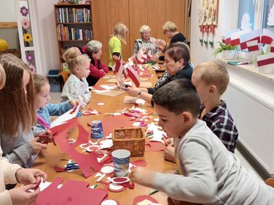 Dzieci z Ostrowca i seniorzy z Klubu Seniora podczas wykonywania kotylionów i flag.