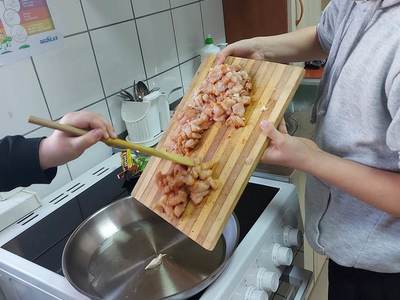 Wychowanek z PWD z Lasek podczas smażenia kurczaka.