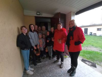 Wychowankowie z PWD z Lasek wręczają seniorce drzewko szczęścia.
