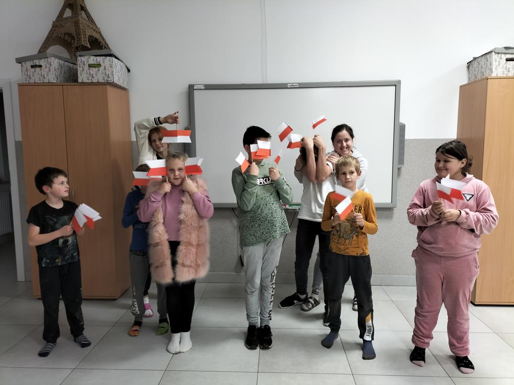 Dzień Niepodległości u dzieci z Placówki Wsparcia Dziennego w Kusicach, które pozują z flagami.