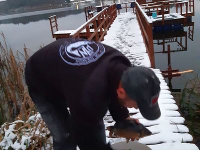 Członek PZW - Oddziału w Sławnie pozuje z rybami przed wpuszczeniem do jeziora. 