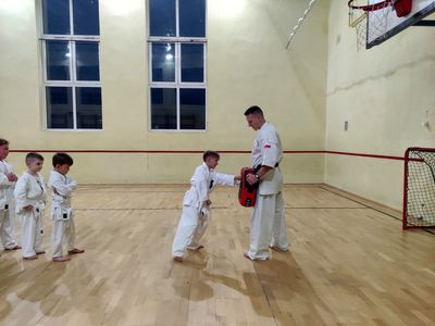 Chłopiec ćwiczy uderzenia z trenerem karate.