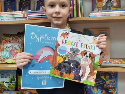 Uczestnik akcji "Mała książka Wielki człowiek" pozuje z książeczkami. 