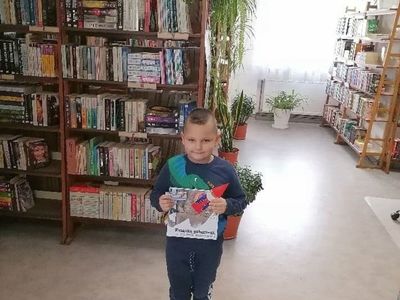 Uczestnik akcji "Mała książka Wielki człowiek" pozuje z książeczkami. 