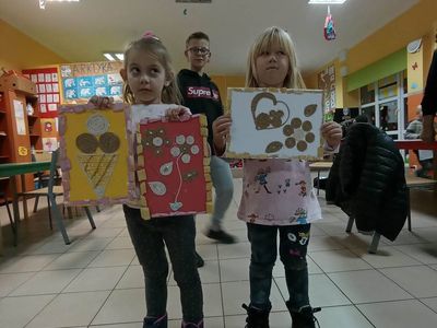 Dzieci z Placówki Wsparcia Dziennego z Lasek prezentują prace techniczne wykonane za pomocą sznurka i kleju.