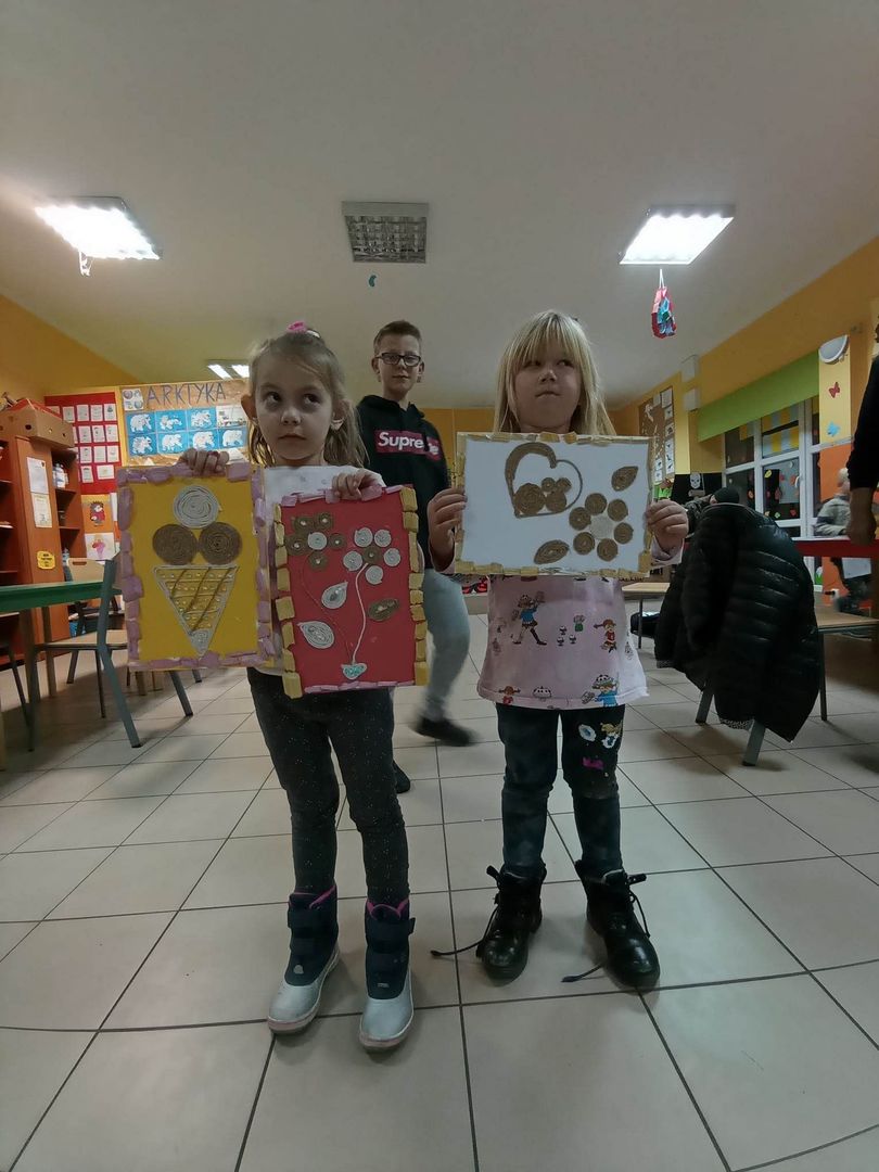 Dzieci z Placówki Wsparcia Dziennego z Lasek prezentują prace techniczne wykonane za pomocą sznurka i kleju. 
