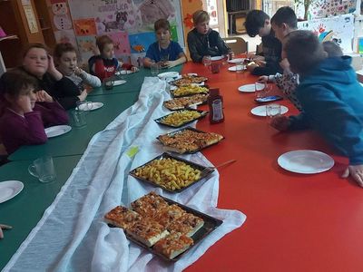 Dzieci z PWD z Lasek częstują się pizzą i frytkami.