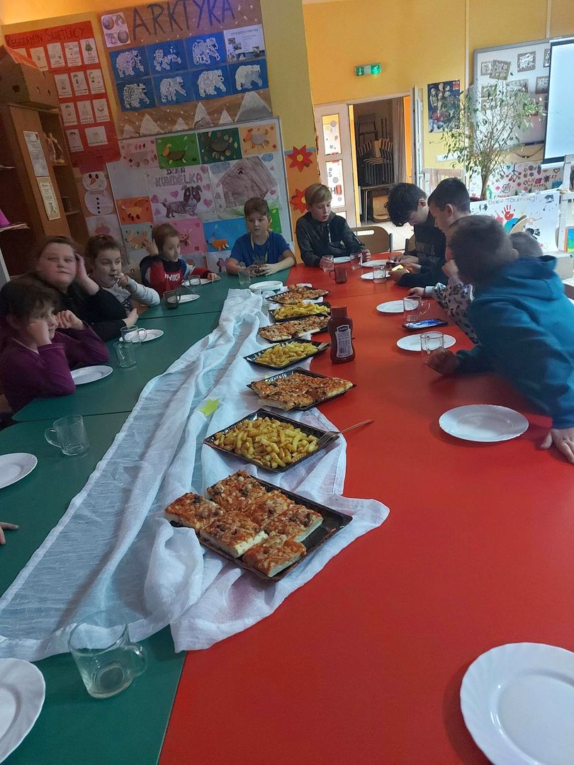 Dzieci z PWD z Lasek częstują się pizzą i frytkami.