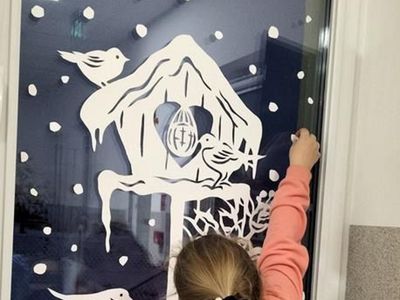 Dziewczynka z Placówki Wsparcia Dziennego w Kusiach przykleja dekorację na oknie. 