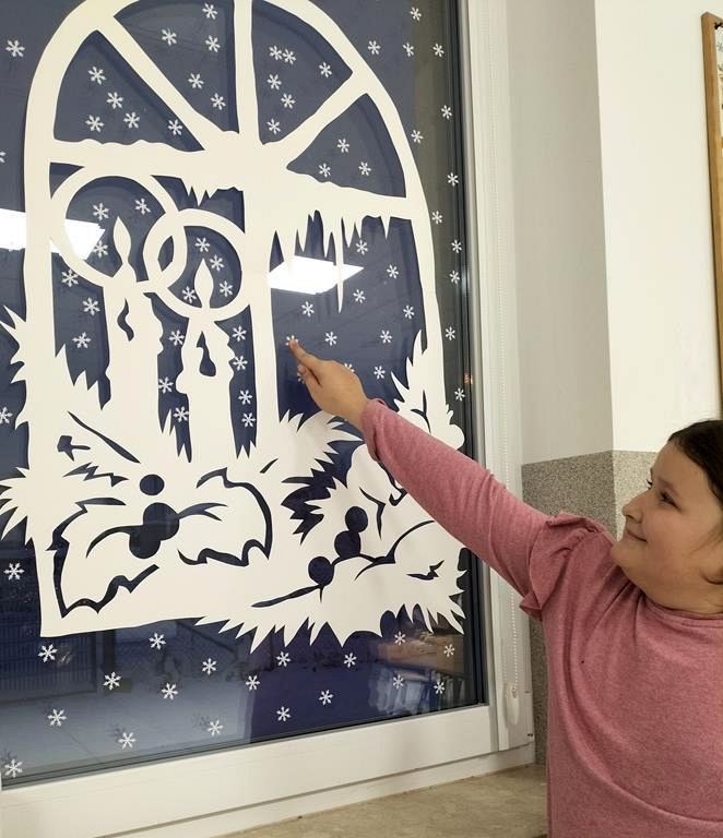 Dziewczynka z Placówki Wsparcia Dziennego w Kusiach przykleja dekorację na oknie.