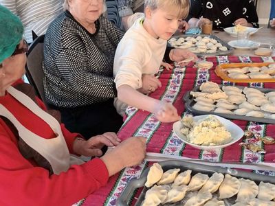 Dzieci z Placówki Wsparcia Dziennego z Ostrowca lepią pierogi z seniorkami. 