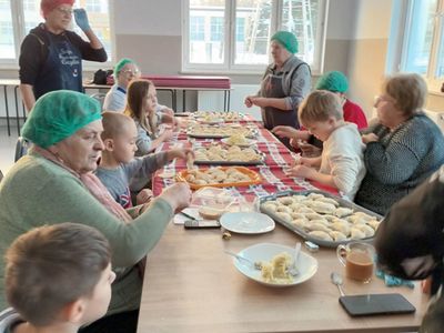 Dzieci z Placówki Wsparcia Dziennego z Ostrowca lepią pierogi z seniorkami. 