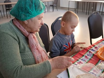 Dzieci z Placówki Wsparcia Dziennego z Ostrowca lepią pierogi z seniorkami. 