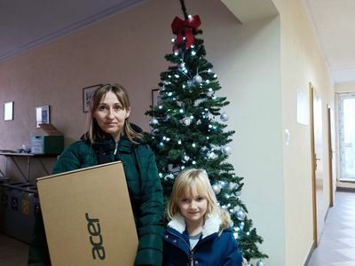 Mama z dzieckiem pozują z laptopem przy choince w malechowskim Urzędzie.