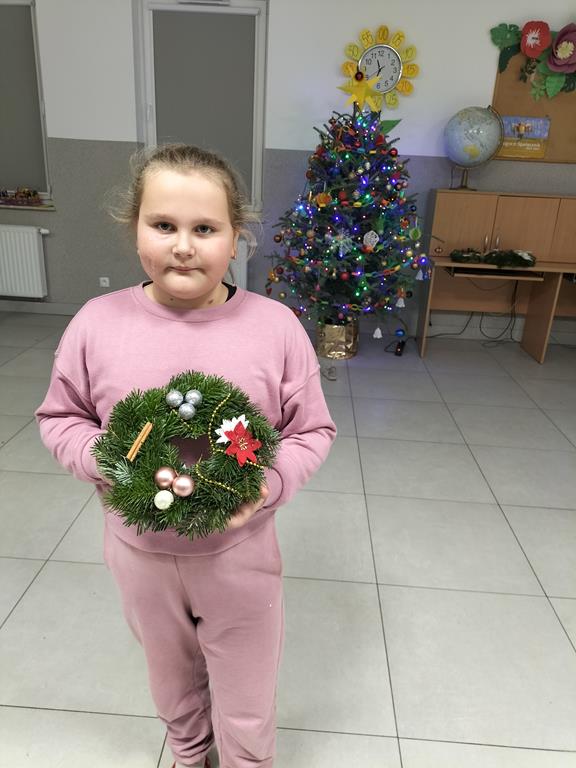 Dziewczynka z Placówki Wsparcia Dziennego w Kusicach pozuje z wykonanym stroikiem. 