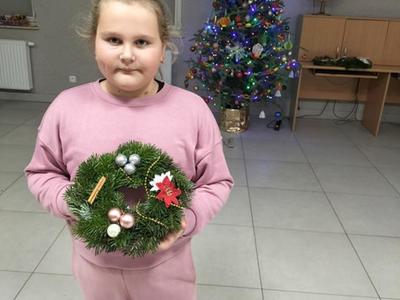 Dziewczynka z Placówki Wsparcia Dziennego w Kusicach pozuje z wykonanym stroikiem.