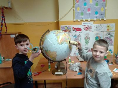 Dzieci  z Placówki Wsparcia Dziennego w Podgórkach pokazują ruch sztucznej satelity na orbicie ziemskiej.
