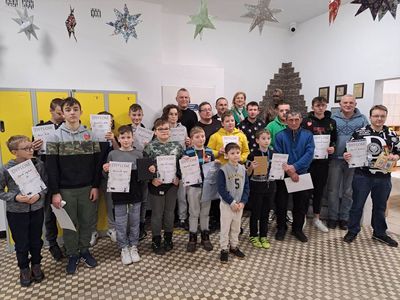 Zdjęcie przedstawia wszystkich wszystkich zawodników turnieju wraz z dyplomami oraz nagrodami, dyrektor SP Lejkowo oraz sędziego.