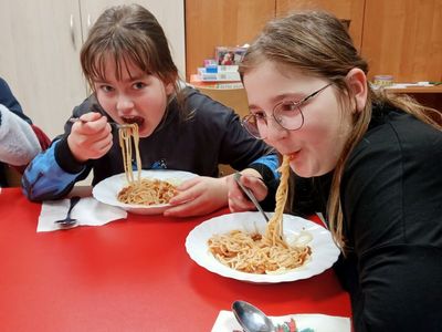 Kasia i Liwia z Placówki Wsparcia Dziennego w Niemicy jedzą spaghetti.

