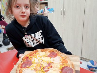Dziewczynka z Placówki Wsparcia Dziennego w Niemicy przy gotowej pizzy.