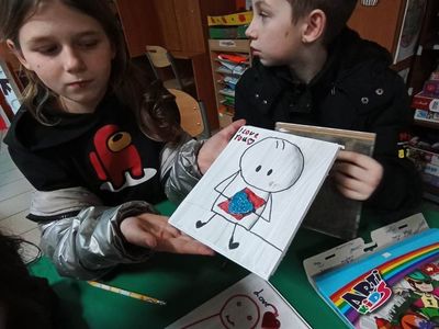 Dziewczynka z PWD z Lasek prezentuje upominek wykonany mazakami na deseczce.